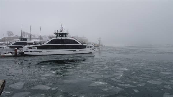 White ferry docked among drifting ice floes, fog over the harbor