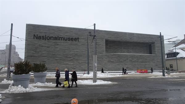 Visitors walk on snow in front of the grey Nasjonalmuseet facade