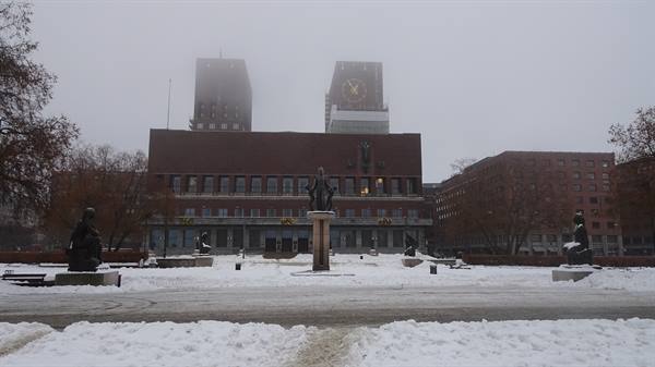 Oslo City Hall in snow, bronze statues, clock tower in the fog