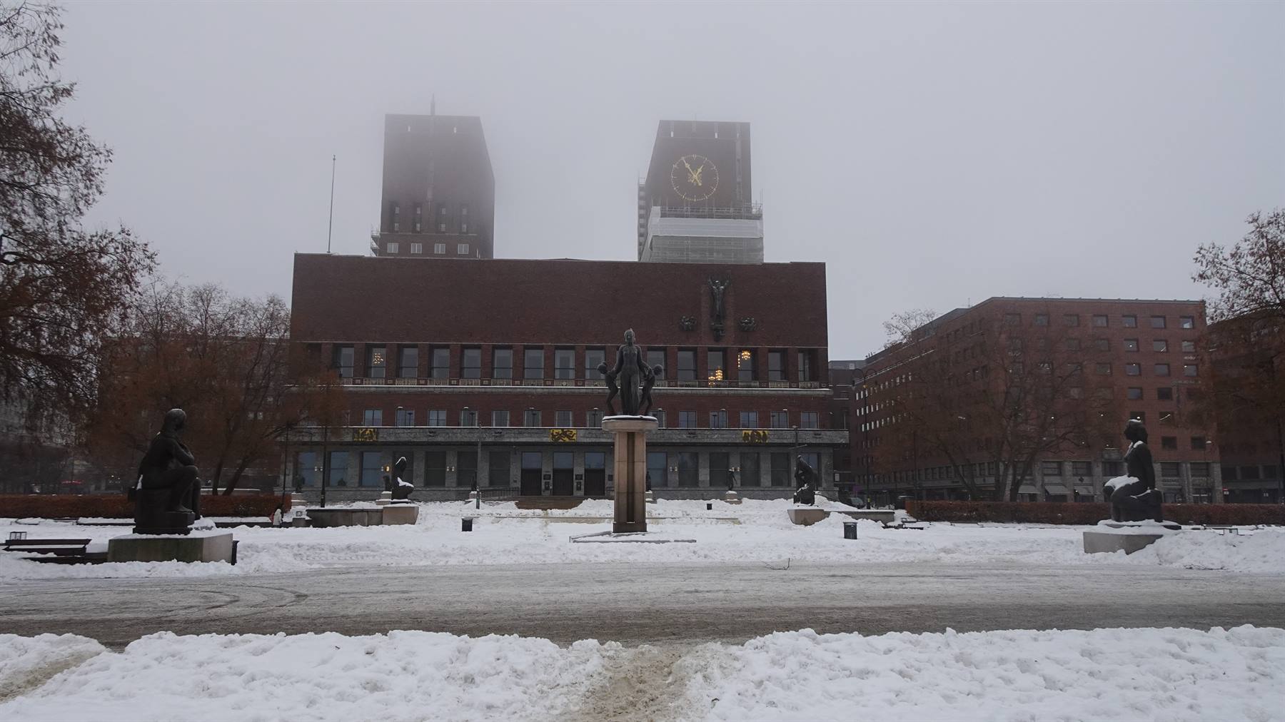 Oslo City Hall in snow, bronze statues, clock tower in the fog
