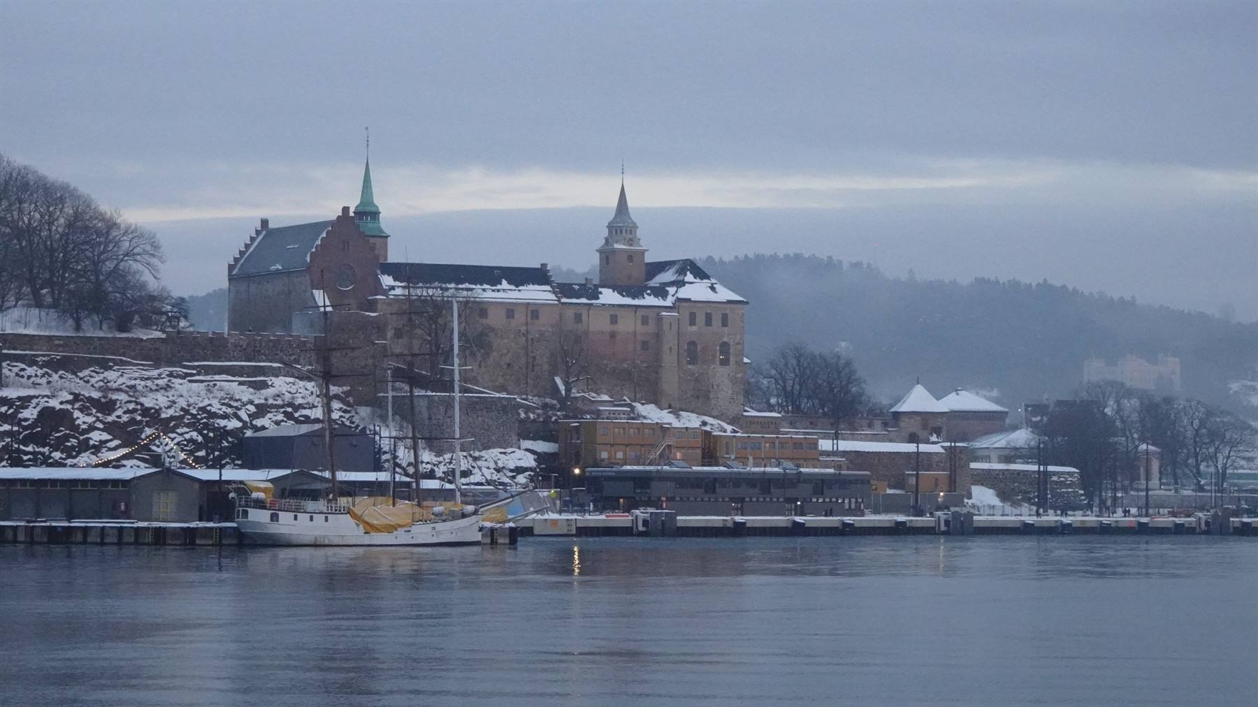 La fortezza di Akershus innevata si riflette nel porto grigio di Oslo