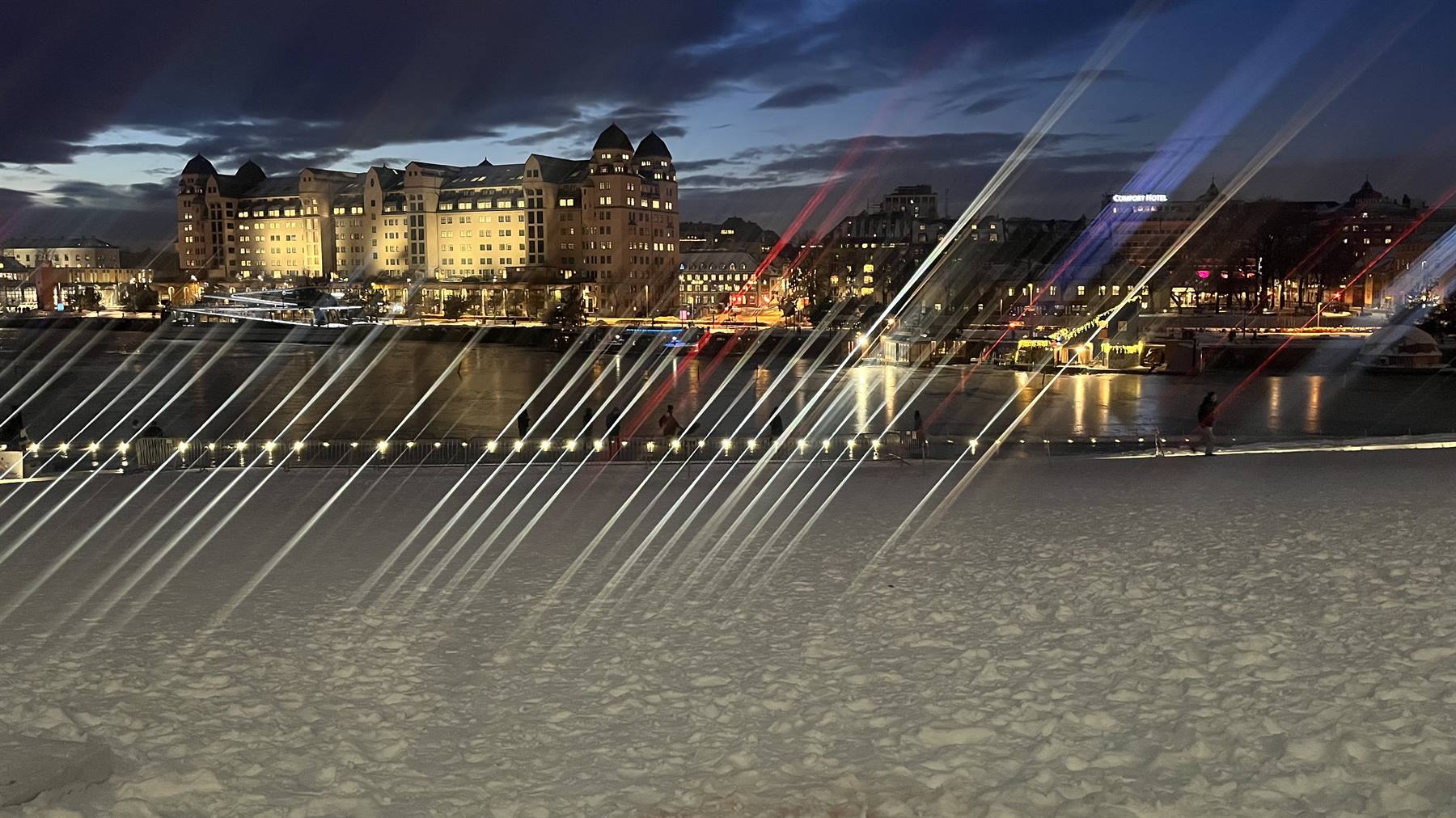 Tetti marmorei dell'Opera di Oslo, strisce di luce e edifici illuminati sull'acqua