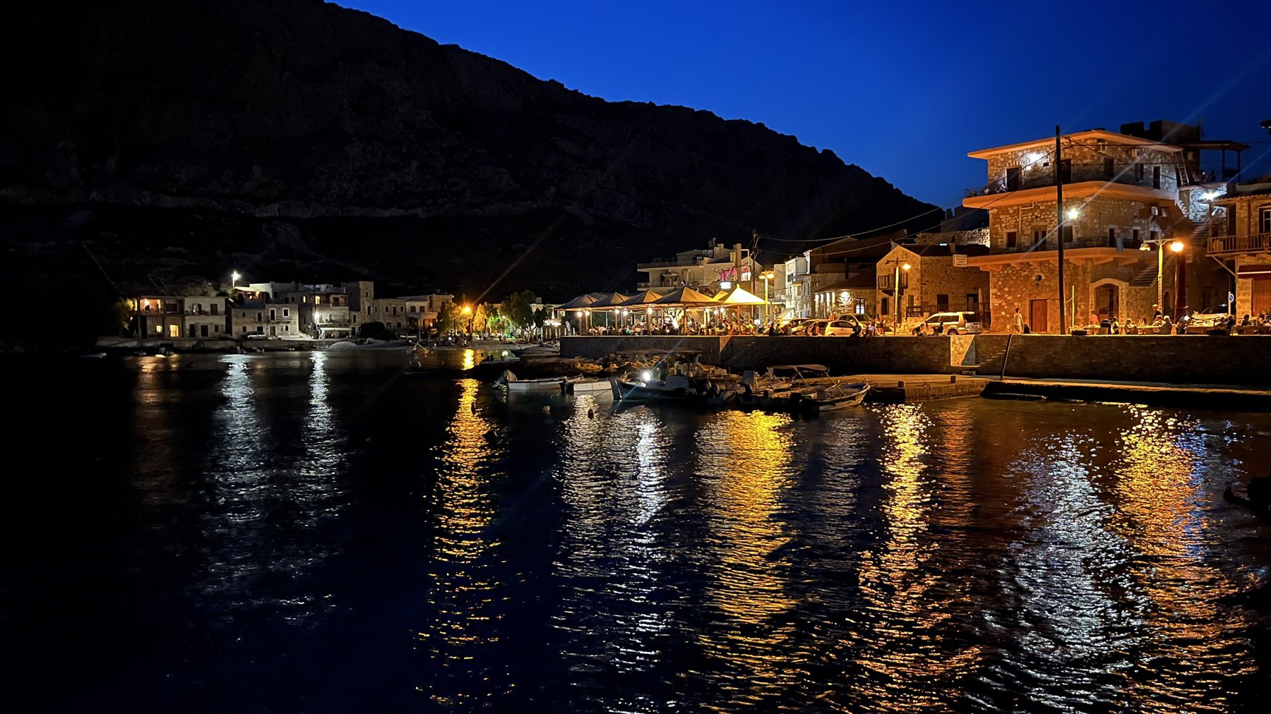 Il porto si accende al tramonto: luci danzanti sull'acqua, cuore felice.