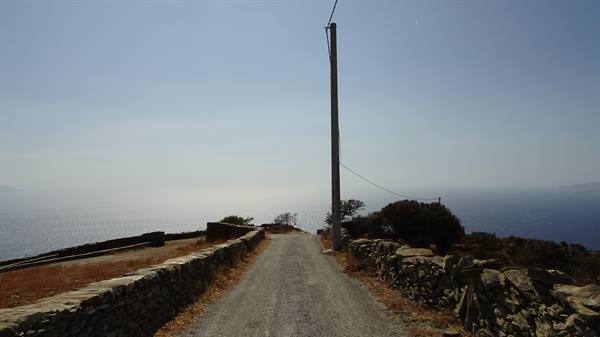 Dirt road between stone walls descends toward the sea