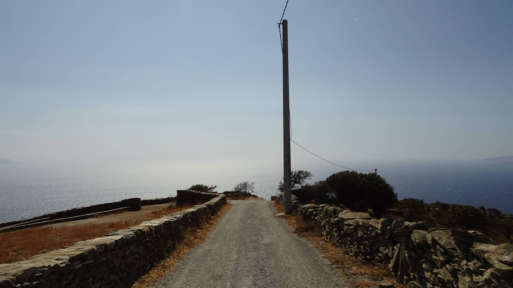 Strada sterrata tra muretti di pietra scende verso il mare
