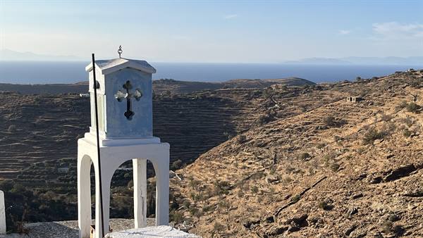 A little white bell tower guards the silence in front of the Aegean Sea.