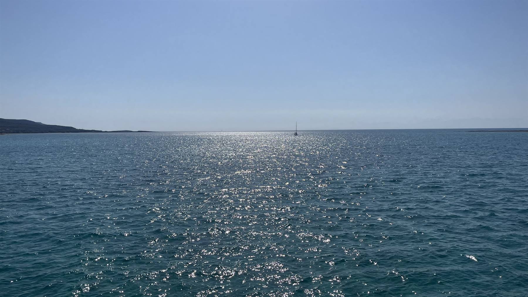 Il mare scintilla d'oro e un'ombra solitaria naviga l'orizzonte.