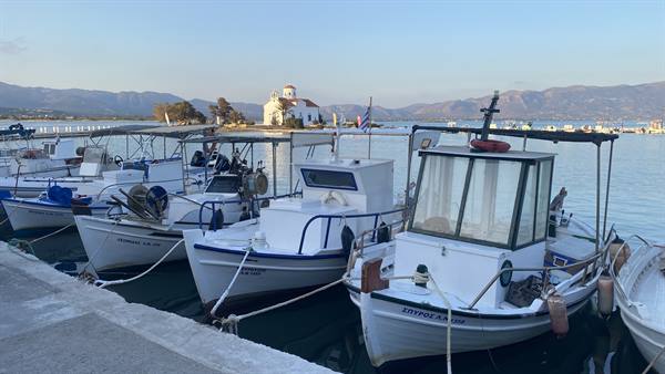 White boats at rest, a church on the water: a Greece that dreams.