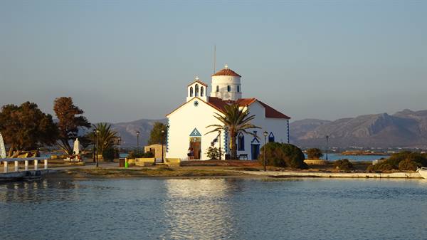The little white church reflected in the water at sunset: pure Greek magic.