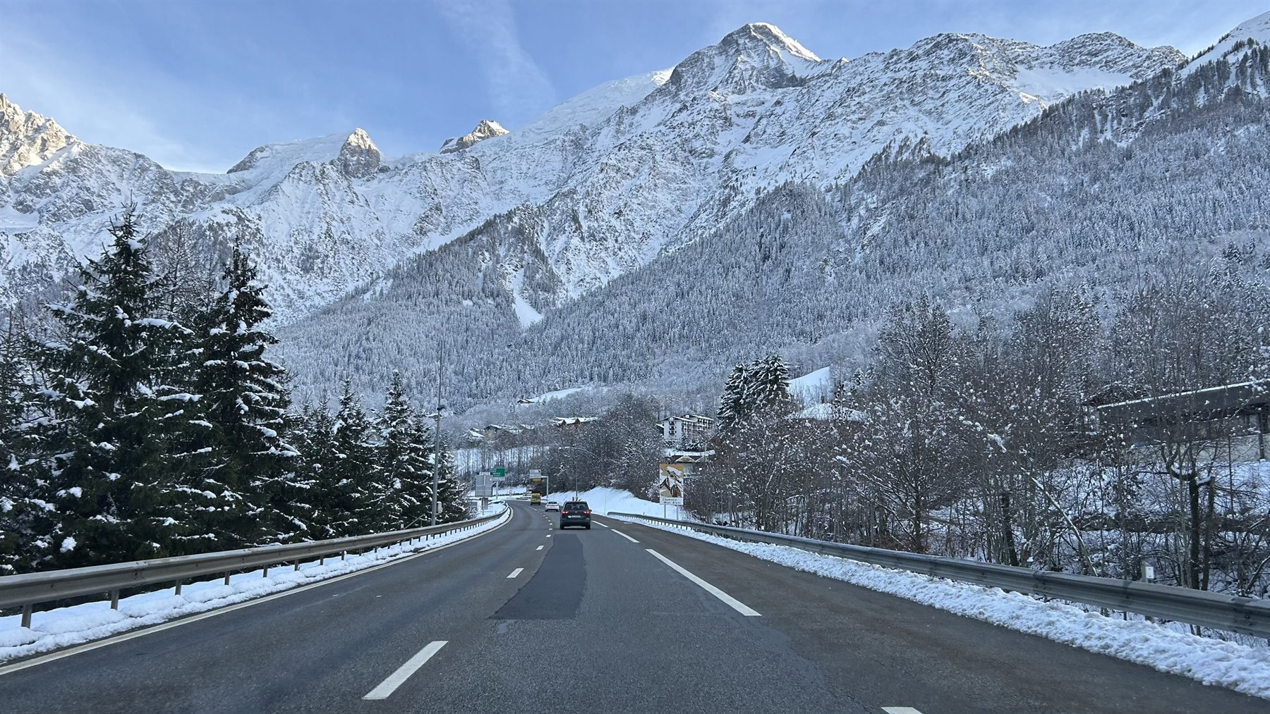 Strada innevata verso Chamonix, auto tra abeti e vette innevate