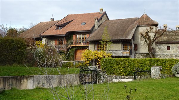 Stone and timber houses with tile roofs in Yvoire, amid green hedges and lawn