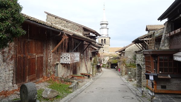 Stone alley in Yvoire with medieval wooden houses and church spire