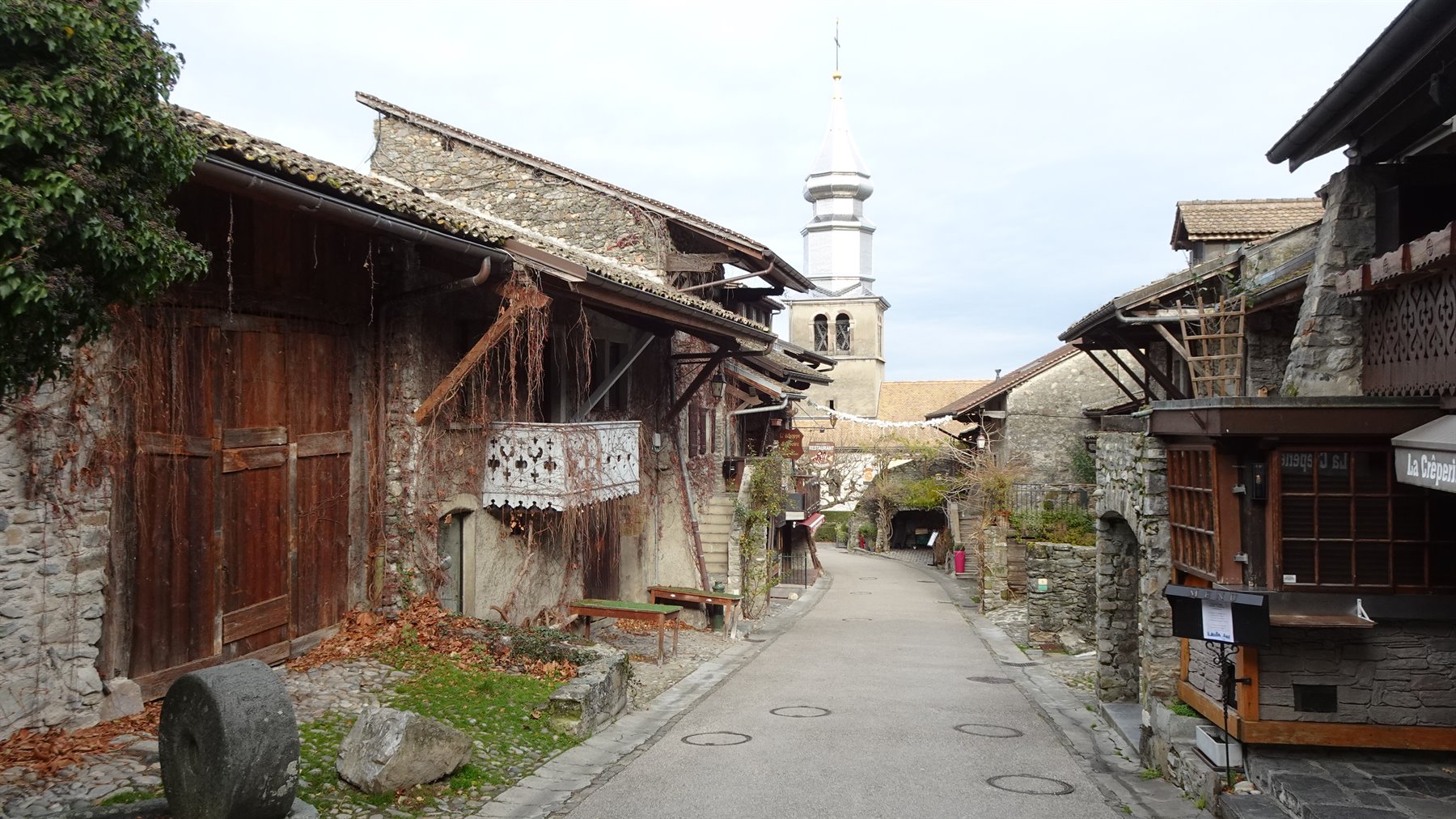Vicolo di pietre a Yvoire con case medievali in legno e campanile