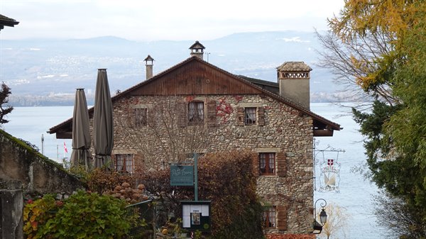 Stone house in Yvoire with closed umbrellas overlooking the lake