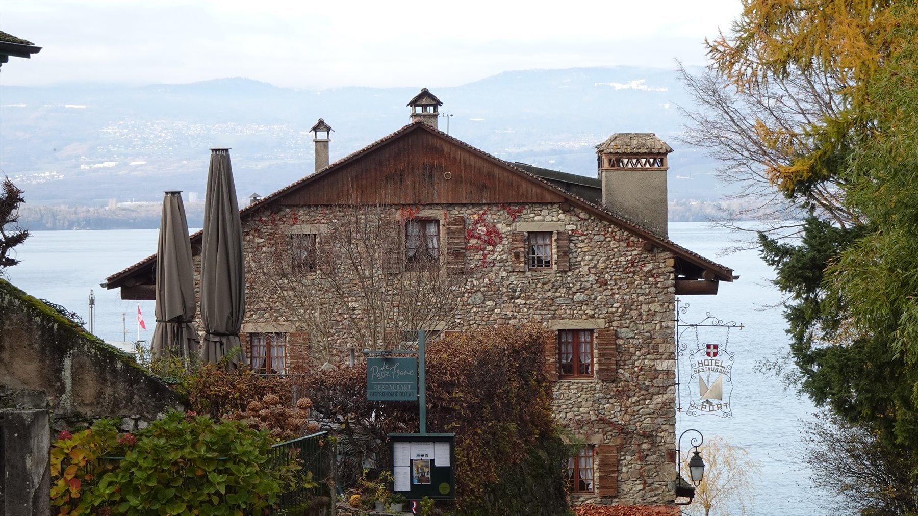 Casa in pietra a Yvoire con ombrelloni chiusi davanti al lago