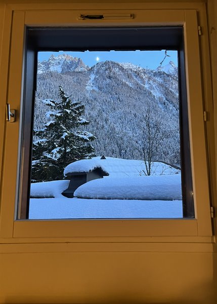 Through a snowy Chamonix window, the moon over alpine peaks