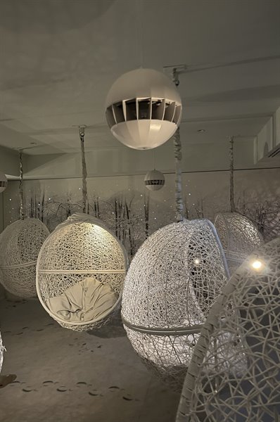White woven hanging chairs in a dim room with warm light