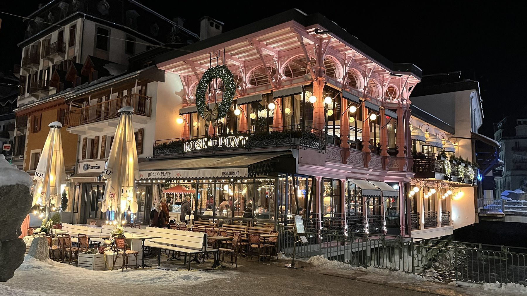 Ristorante in legno rosa illuminato di notte, neve e tavolini vuoti, Chamonix