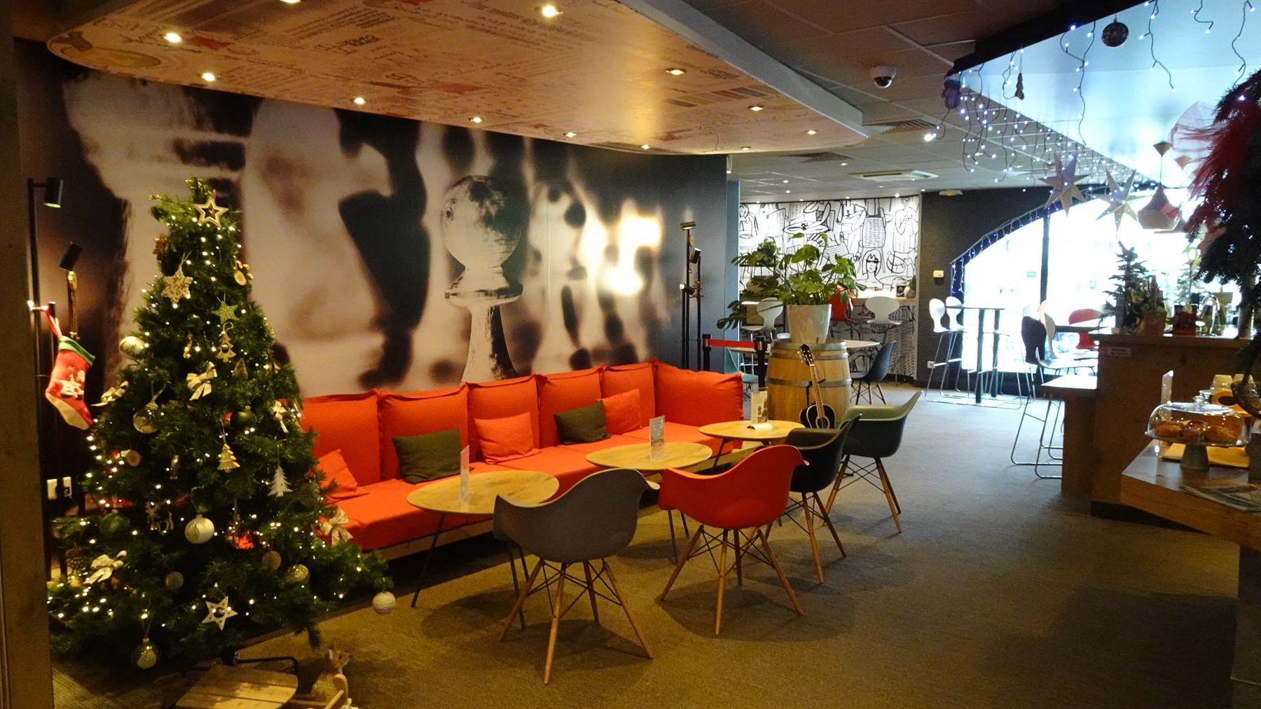 Lounge con albero di Natale illuminato, divano arancione e tavolini rotondi