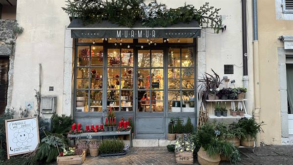 MurMur shop in Yvoire, wooden storefront with plants, red candles and Christmas lights