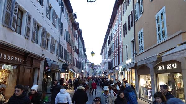 Busy pedestrian street in Annecy, colorful shuttered houses and festive lights