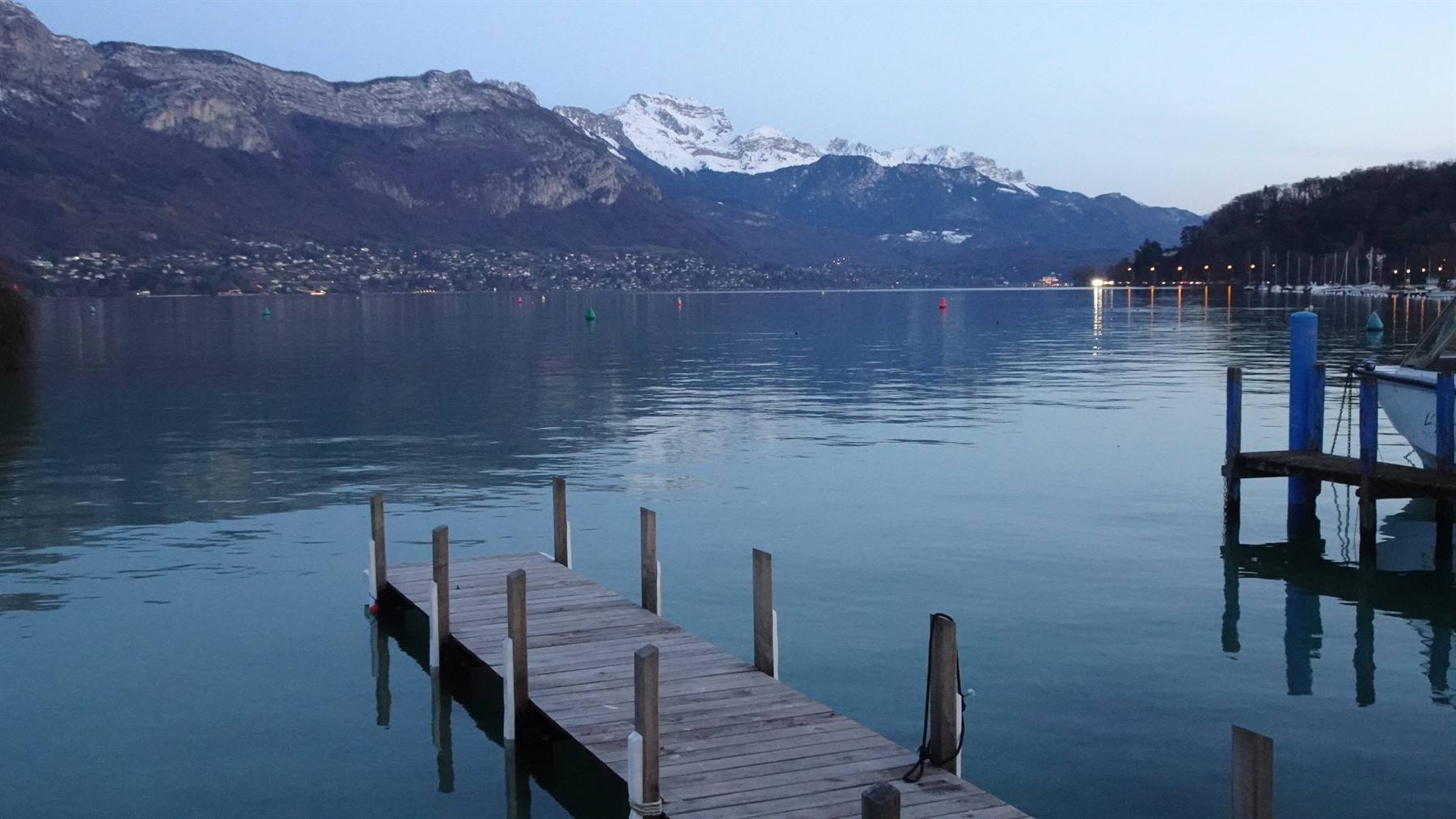 Ponte di legno sul lago di Annecy, montagne innevate all'alba