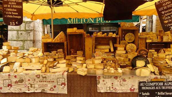 Alpine cheese stall under yellow umbrellas at the Yvoire market