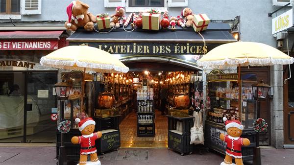 Entrance of L'Atelier des Épices in Yvoire, with yellow umbrellas and Christmas figures
