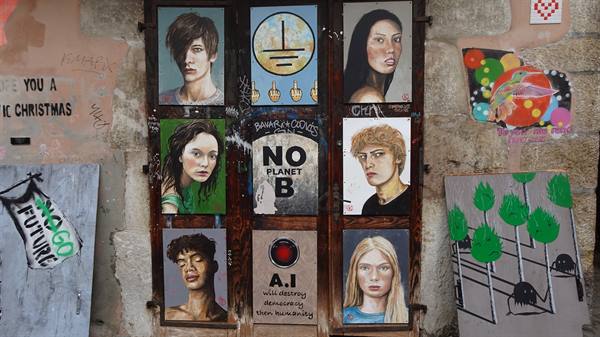 Painted wooden portraits and street art collage on stone wall, Yvoire