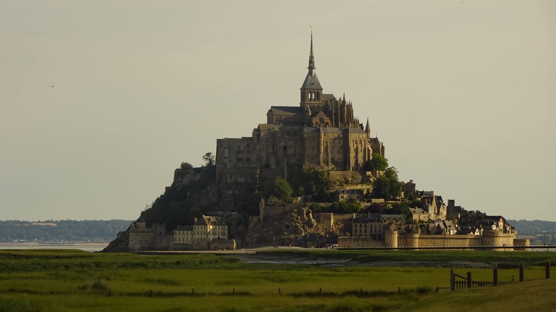 L'abbazia del Mont Saint Michel emerge sopra gli edifici, prato verde in primo piano