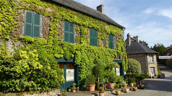 Ivy-covered stone house with green shutters and flower pots, Saint Ceneri le Gerai