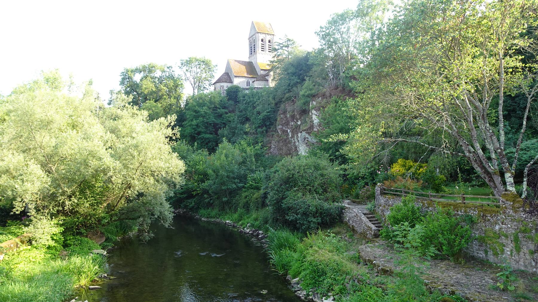 La chiesa di Saint Céneri-le-Gérei domina il fiume tra alberi verdi
