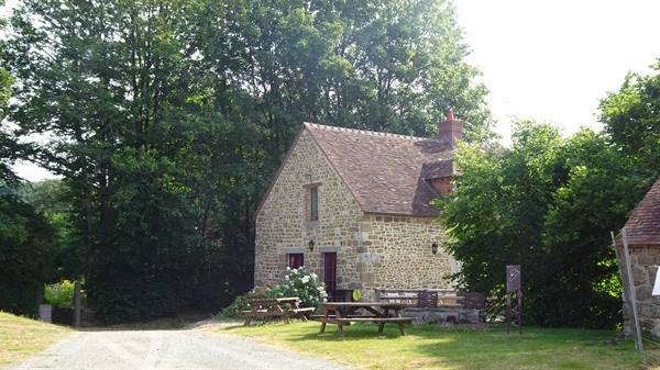 Stone cottage with picnic tables among tall green trees, Saint Ceneri le Gerai