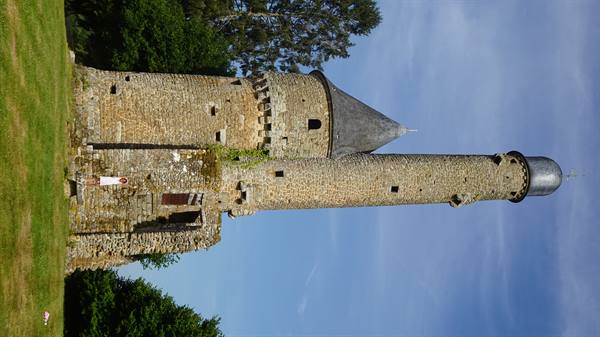 Medieval stone towers with slate roofs, blue sky and green lawn