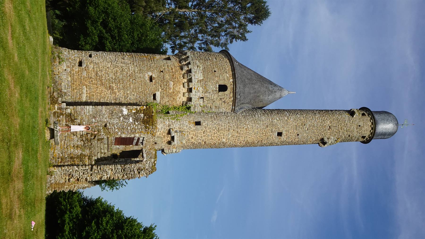 Torri medievali in pietra con tetti di ardesia, cielo azzurro e prato verde