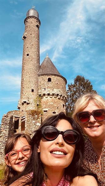 Three smiling women before the stone lantern tower of La Lucerne abbey