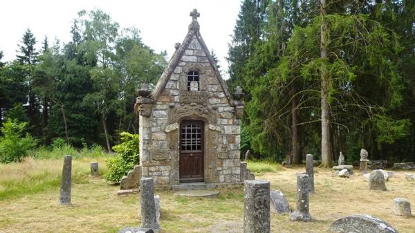 Stone chapel with cross among old gravestones, Saint-Ceneri-le-Gerei