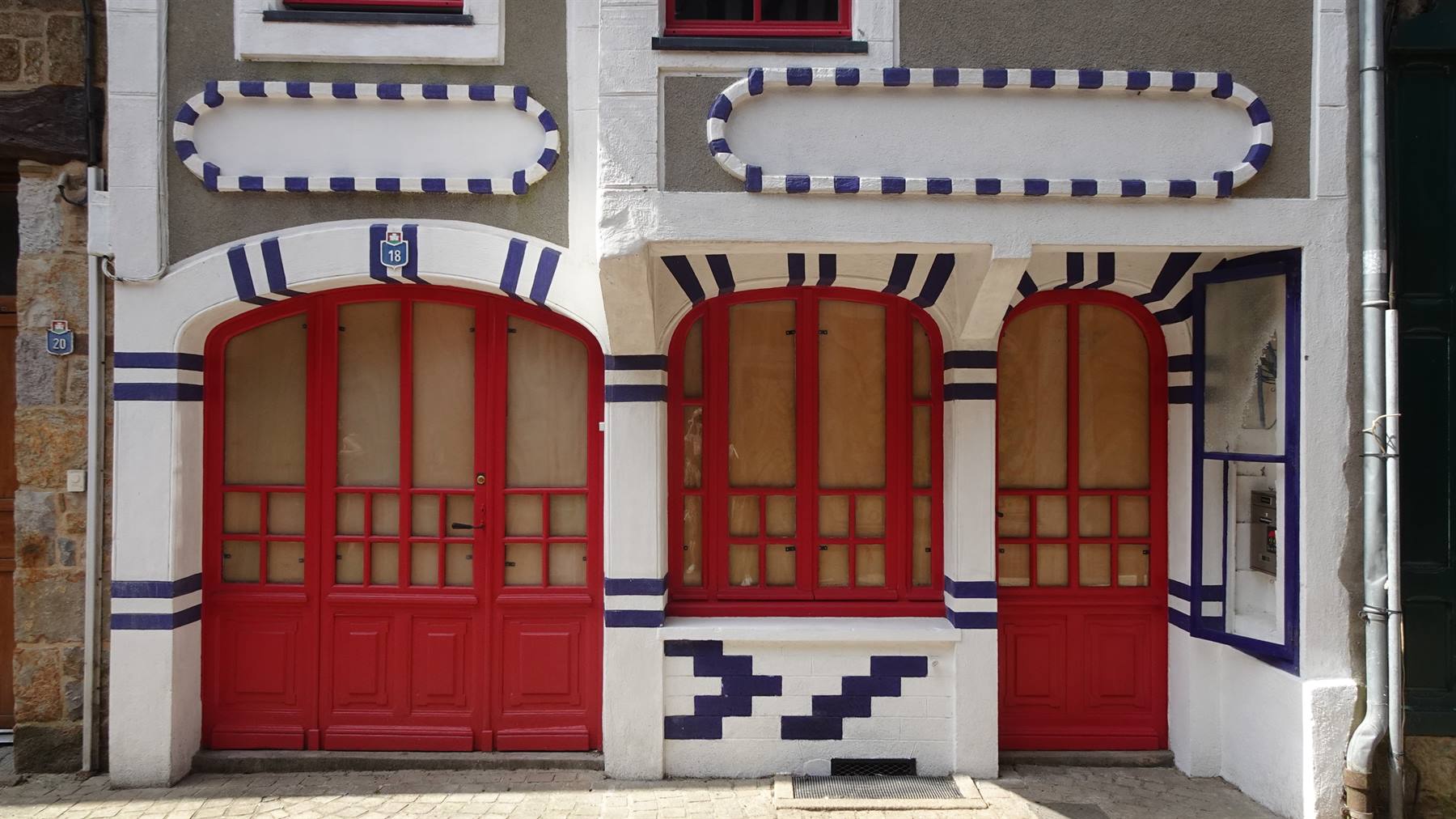 Facciata dipinta di bianco, blu e rosso con porte e finestre ad arco