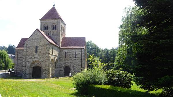 Romanesque stone church with bell tower among trees in Saint-Céneri-le-Gérei
