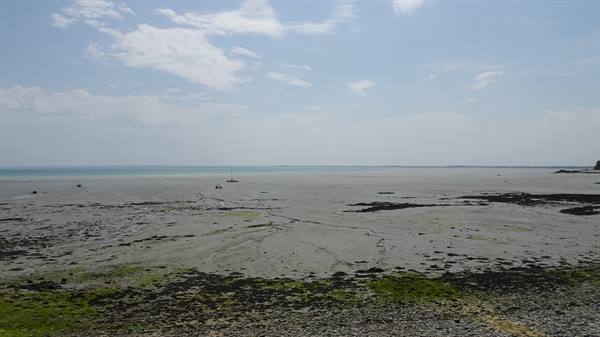 Low tide at Cancale: seaweed and exposed sand, distant boats on the sea