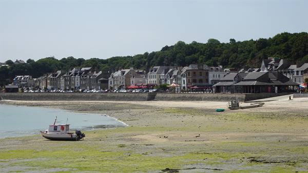 Boat stranded on seaweed at low tide in front of Cancale houses