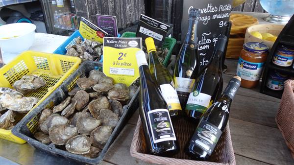Fresh oysters in crates and white wine bottles at Cancale market