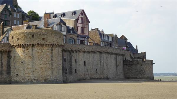 Stone ramparts and half-timbered houses above sandy shore, Mont Saint Michel
