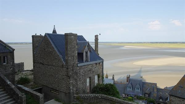 Stone houses of Mont Saint Michel overlooking sandy bay in daylight