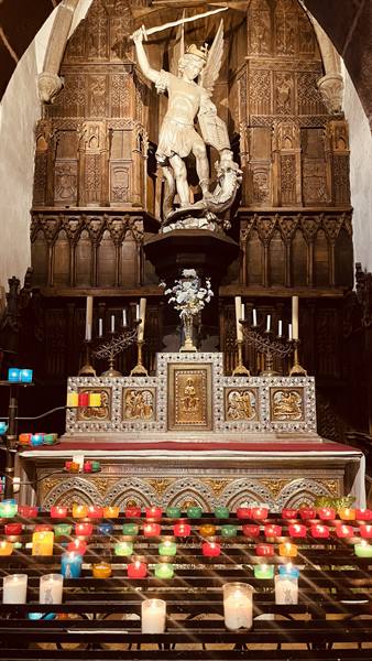 Saint Michael statue towering over the altar with votive candles, Mont Saint Michel
