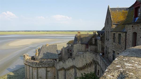 Stone ramparts of Mont Saint Michel above sandy bay in daylight