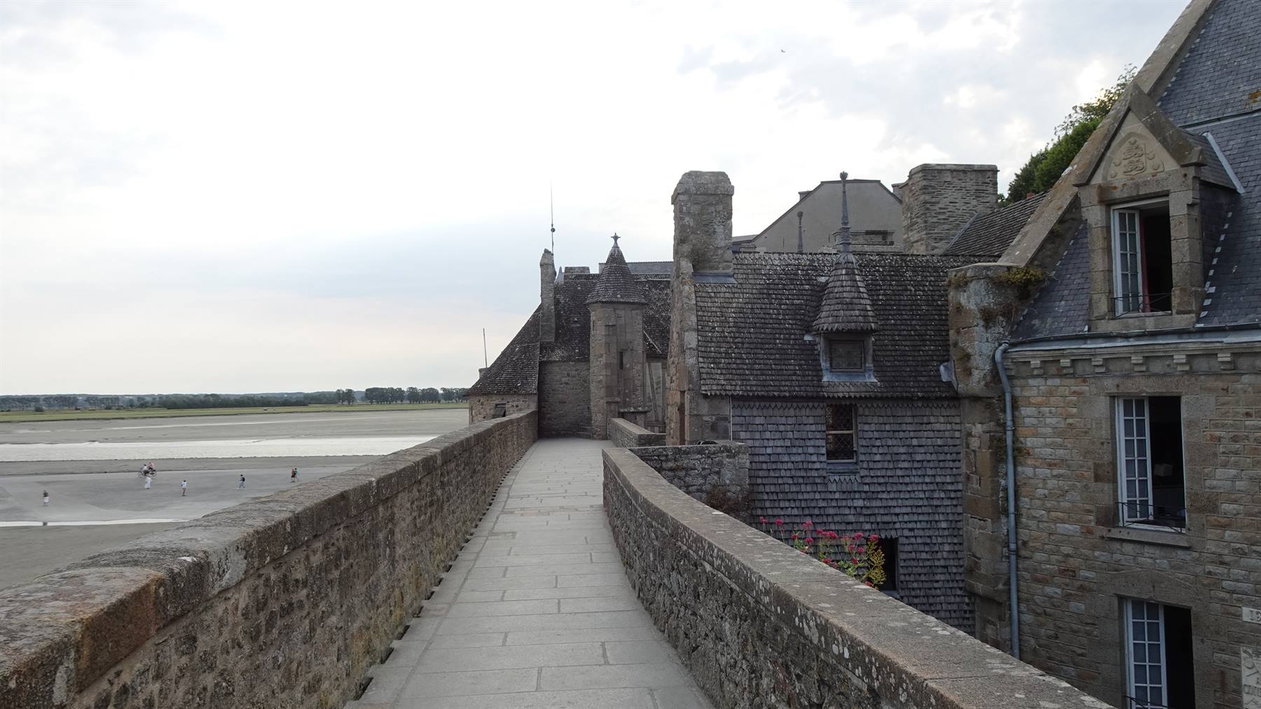 Camminamento sulle mura di pietra del Mont Saint Michel, case slanciate sulla baia