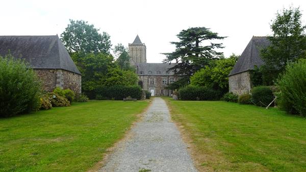 Gravel path leading to the granite abbey between lawns and farm buildings
