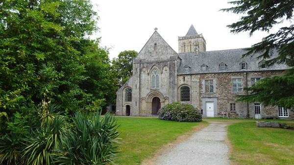 La Lucerne Abbey, stone facade among trees and green lawn