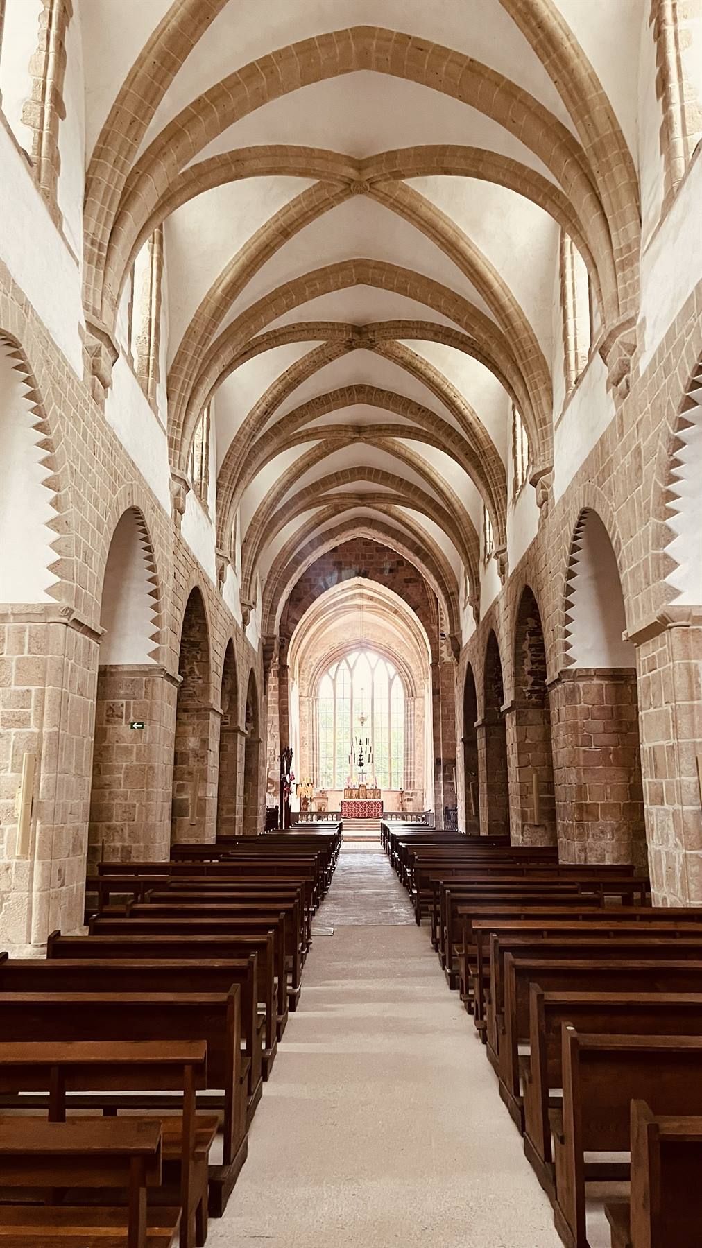 Chiesa abbaziale di La Lucerne: volte romaniche, banchi in legno, luce dalla vetrata